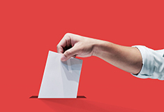 Une main met un bulletin dans une urne